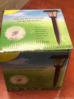 Photo of the original product packaging showing the product name and features including solar power, green energy, dual modes as a bug zapper and garden light, measuring 1142 cm, made in China.