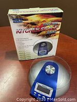 emLna ECC-591 kitchen scale in original packaging showing product image and key features on box.