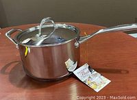 Closed Paderno 4L stainless steel pot with lid on wooden surface, showing pot handles and lid handle with tags attached.