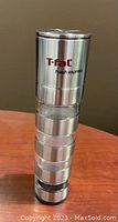 Side view of T-fal Fresh Express spice grinder showing four separate stainless steel compartments stacked vertically.