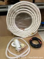 Coiled white insulated copper tubing with control wire and accessories packed together