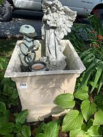 View of the planter pot with angel statue and boy statue inside outdoors, showing layout and finish.