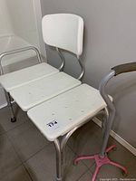 Extended shower bench positioned next to a bathtub with visible backrest and three white plastic slats for sitting.
