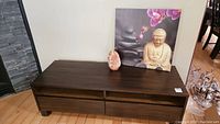 Wooden coffee table or TV stand with drawers, salt lamp, and Buddha orchid artwork on top