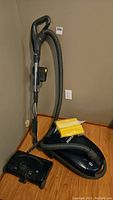 Kenmore vacuum cleaner standing upright with hose and wand attached, spare yellow vacuum bags placed on the base.