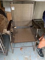 Close-up photo of a single folding outdoor chair showing brown mesh canvas seat and back with metal arms and legs