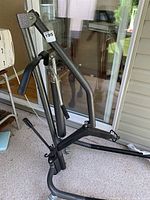 Patient lift with black metal frame and padded handles shown on porch floor.