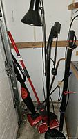 Black power bar, floor lamp, Vileda mop, and cleaning tools grouped in corner