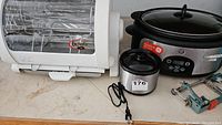 Mini dip warmer, George Foreman Jr rotisserie, and GE crockpot on countertop with small blue tools partially visible