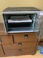 Front and open view of Luby GH55 toaster oven showing the metal wire rack inside and control knobs on the right side.