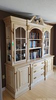 Front view of whole buffet hutch unit, showing glass doors at top and drawers, wooden doors below.