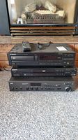 Three electronics stacked: Pioneer PD-101 CD deck on top, Sony DVP-S360 DVD player below, and NAD 7225 PE receiver at bottom in front of a fireplace.