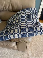Closeup of hand woven throw blanket showing blue and white geometric pattern and textured weave.