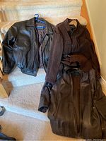 Three men's leather jackets displayed on carpeted stairs, showing overall look and color variations.