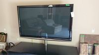 Front view of a Panasonic Viera P54G10 plasma TV mounted on a stand, showing the screen and part of the surroundings reflected on the screen.