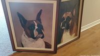 Two framed photos of Boxer dogs placed on the floor, showing overall lot contents and framing style.