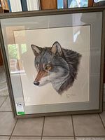 Frontal view of framed and matted wolf head print with sticker on bottom left of frame.