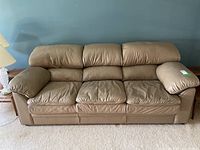Full front view of the brown leather 3-seat sofa showing three seat cushions, three back cushions, and padded armrests.