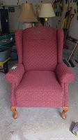 Front view of the red wing back sofa chair showing the fabric upholstery and overall shape.