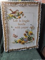 Front of framed needlepoint showing embroidery and decorative ruffled trim