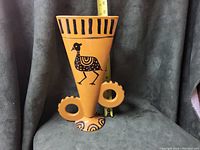 Front view of the vase showing the bird design, circular handles, and shape with measuring tape indicating height.