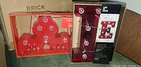 Red octopus LED light decoration in box on green surface with a cardboard box behind.