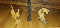 Photo showing all three carvings: wooden eagle, dark wood figure, and painted dragon figurine