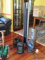 Two Lasko air purifiers, two fans, and one Comfort Zone ceramic heater arranged on wood floor.