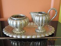 Full set of creamer, sugar bowl and tray on display against orange background