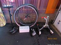 Photo showing bicycle tires, air pump, and bike hoist components on floor against wall.