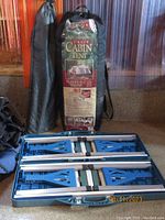 Photo showing Ozark Trail Cabin Tent in storage bag and folded camping table in case.