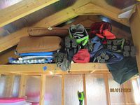 Multiple folded camp chairs stacked on a wooden rack, various colors and conditions visible.
