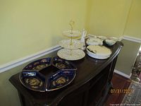 Overall view of the table showing all dishes including the 3-tier dessert dish, blue and gold Courting Couple condiment dishes, and other condiment and covered bowls.