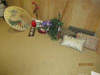 Wide shot showing assortment of decorative pillows, vases, faux plants, carved wood cat, vintage weather station, and Asian paper umbrella
