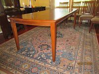 View of the wooden dining table showing the smooth polished surface and tapered legs.