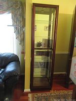 Front view of the tall glass display cabinet with wooden frame showing glass shelves inside and mirror back.
