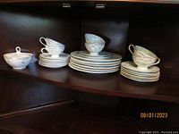 Set of stacked plates and cups including a sugar bowl, showing the overall quantity and arrangement of the set.