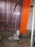 Full view of the Jiffy Steamer Model J-2 standing upright with hose extended and Windmere Fabric Pill Remover box on the floor