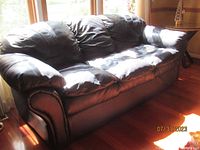 Front view of navy blue leather sofa with visible removable cushions and padded backrest in natural light.