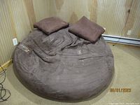 Overview of the large brown Lovesac SuperSac chair with two matching square pillows on a carpeted floor