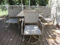 Outdoor patio table surrounded by four metal mesh chairs on a wooden deck