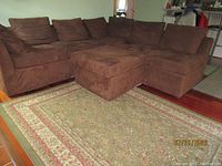 Brown sectional sofa with matching ottoman on patterned rug, showing overall condition and style