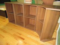 Photo showing the set of three rectangular wood grain shelves and one corner shelf assembled together on a hardwood floor.