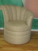 Front view of upholstered swivel barrel chair showing curved back and seat cushion in beige and light brown geometric pattern.