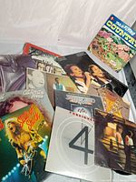 Vinyl record albums from various artists including Saturday Night Fever soundtrack, Foreigner, and Cat Scratch Fever by Ted Nugent, displayed fanned out on a flat surface.
