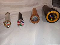 Four kaleidoscopes side by side showing their viewing ends with colorful internal patterns.