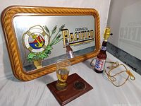 Wide angle showing the Pacifico Cerveza advertising mirror with real rope border, Bud Light bottle lamp with wiring, faux resin beer glass on wood base with medallion.