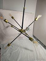 Angled side view of the Elegant Lighting Axel 10 light sputnik chandelier showing multiple exposed filament bulbs and brass-tone sockets on a black metal frame.