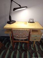 Desk with two drawers, lamp, chair, and letter/file holder shown in use setting