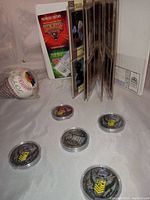 Five NHRA NASCAR racing collector coins arranged on white background with the collectible cards book and a baseball nearby